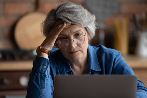 3 Signs You’re Not Ready to Apply for Social Security Yet Frustrated person with hand on head looking at laptop.jpg